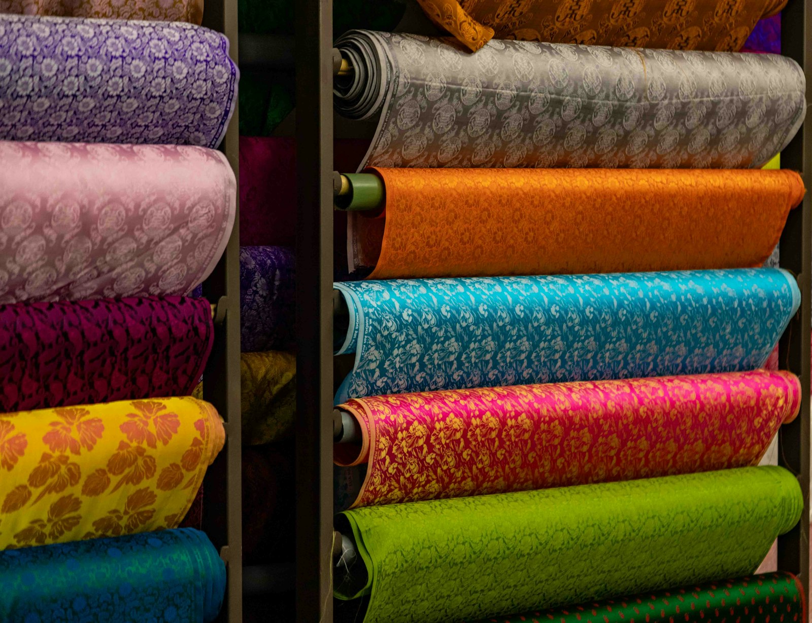Rouleaux de tissus imprimés aux motifs colorés rangés sur des étagères
